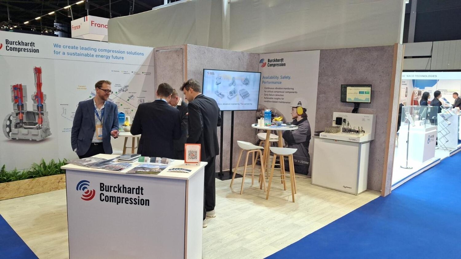 Employees from Burckhardt Compression and PROGNOST Systems at the trade show booth.