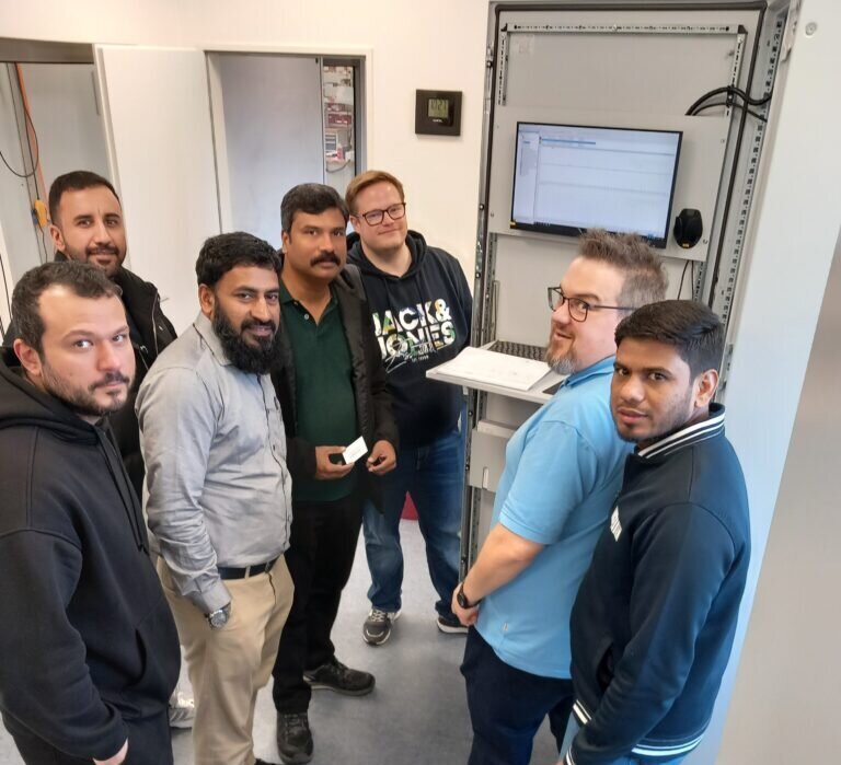 Guests for a factory acceptance test in our headquarters in Rheine standing in front of a cabinet with their system..