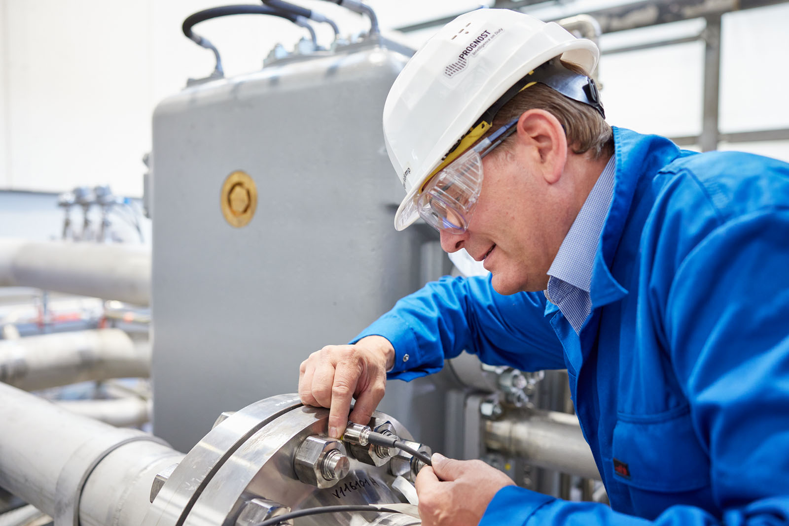 Close-up of a support expert checking an installed sensor on an industrial compressor.