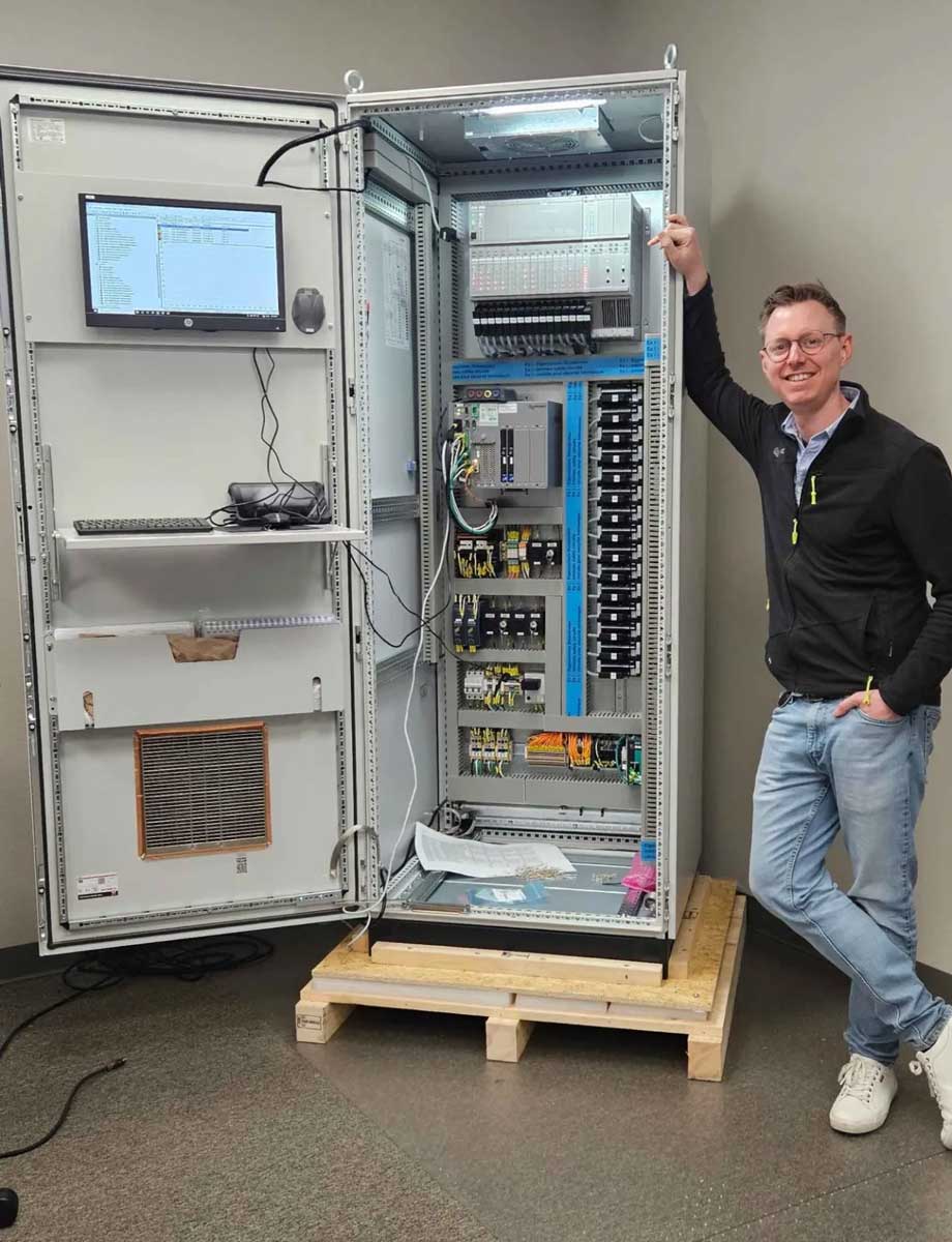 A man ist standing in front of a cabinet with a PROGNOST-NT monitoring system.